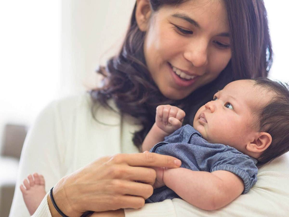 A woman smiling and holding an infant in her arms.