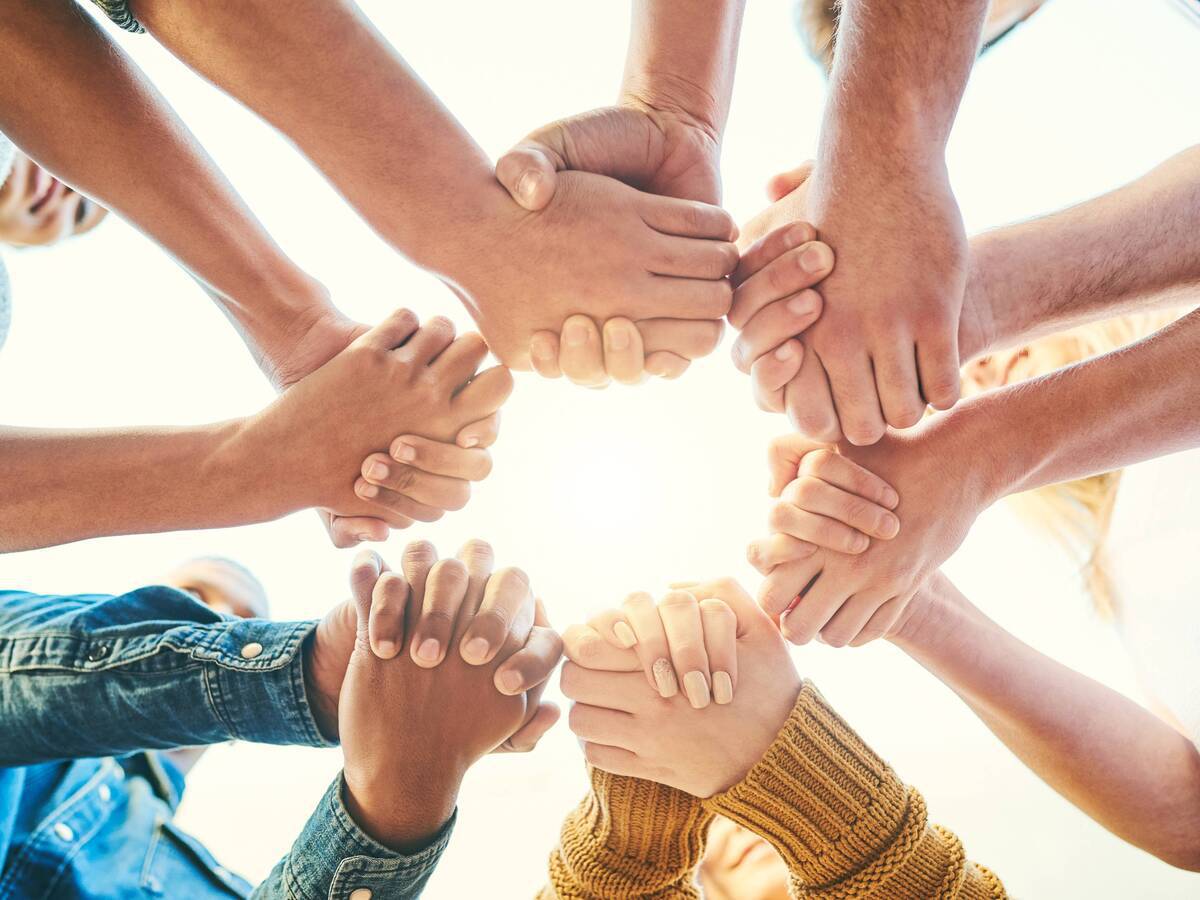 Several people holding hands in the middle of a circle.